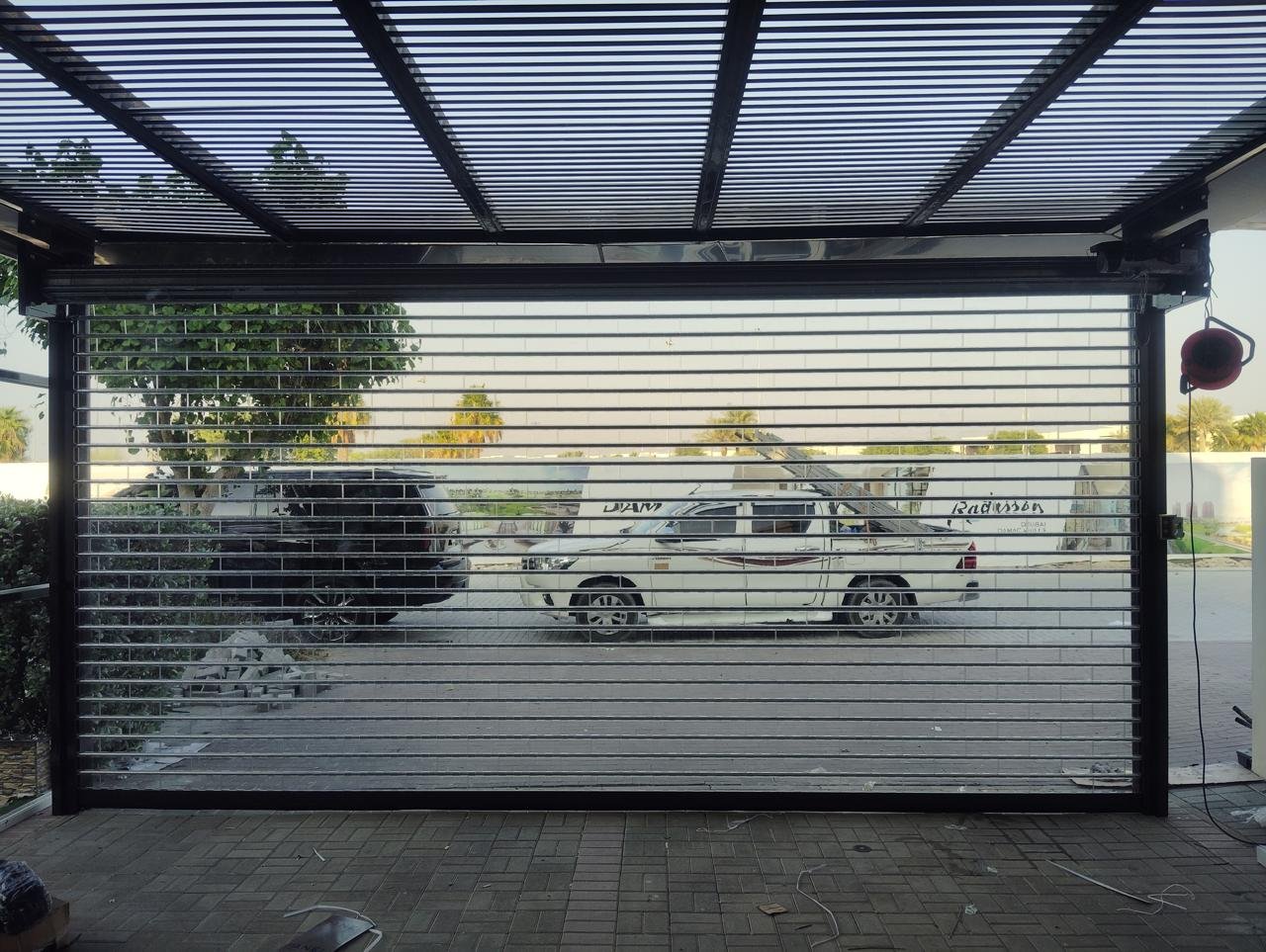 Polycarbonate roller shutter on a carport with black frame