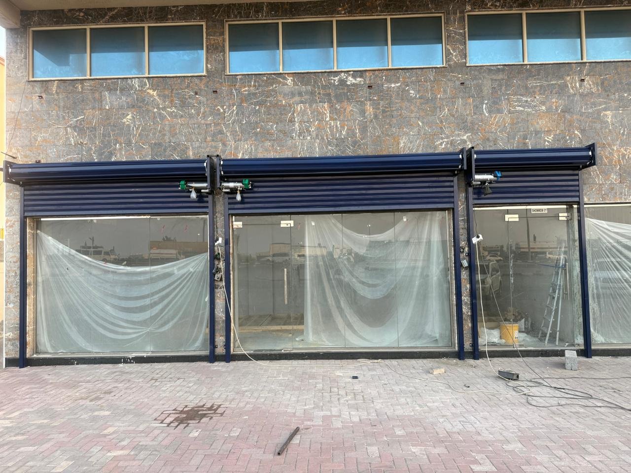 Navy blue motorized rolling shutters installed on a shopfront in Dubai